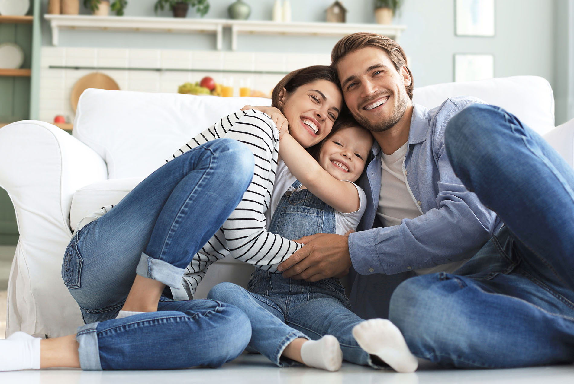 A family of four posing together on a couch with smiles and affectionate gestures.