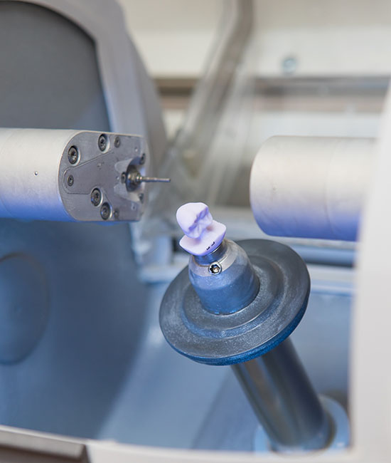 An industrial machine with a component being processed, featuring a robotic arm and a cylindrical object on a conveyor belt.